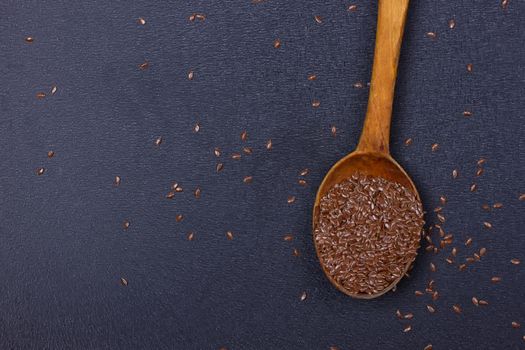 wooden spoon with flax seed placed on a black table