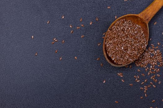 wooden spoon with flax seed placed on a black table