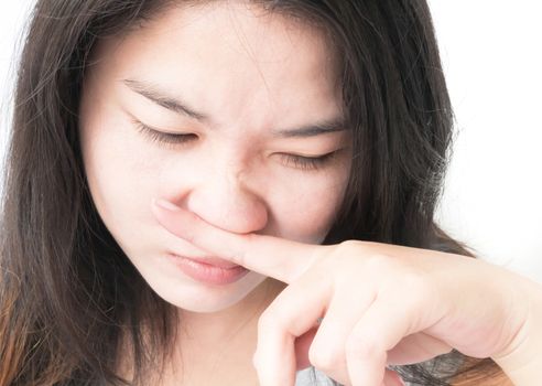 Closeup woman closes a nose with finger, smell concept