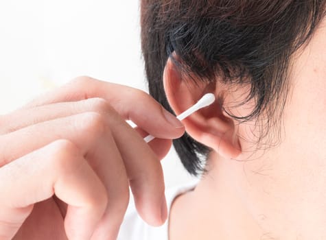 Closeup man cleaning ear with cotton bud, health care concept