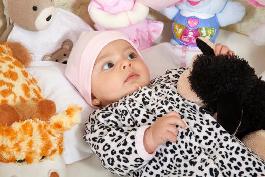 A baby girl dressed in animal print surrounded by stuffed animals