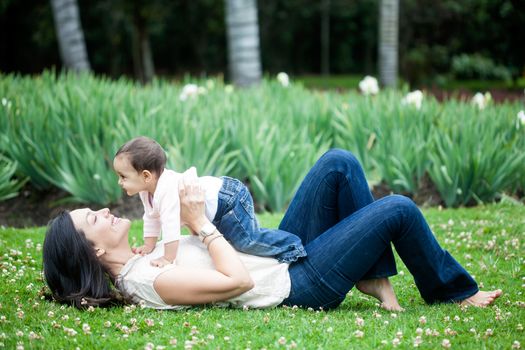 Baby girl playing with her mom on the grass