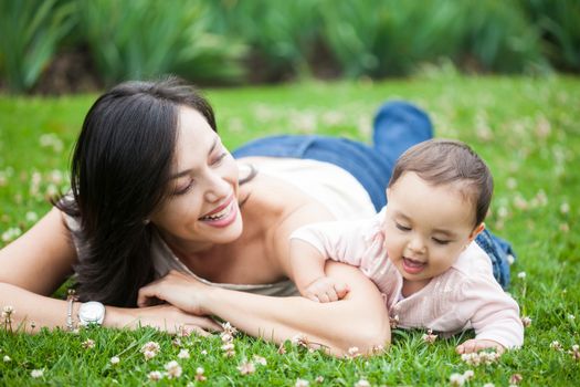 Baby girl playing with her mom on the grass