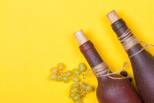 bottle of white wine with grapes on a yellowbackground