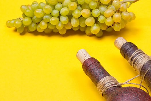 bottle of white wine with grapes on a yellowbackground