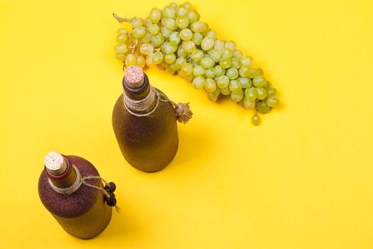 bottle of white wine with grapes on a yellowbackground