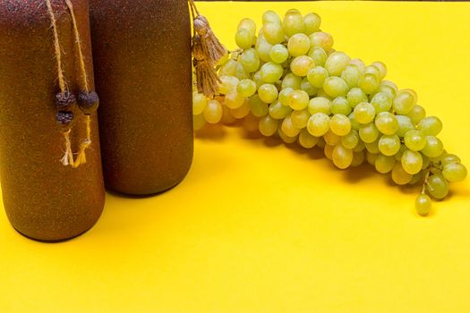 bottle of white wine with grapes on a yellowbackground