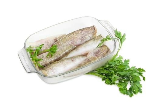 Several carcasses of the notothenia fish without of a heads and tails and with peeled scales and prepared for baking in the rectangular glass for baking and parsley on a white background
