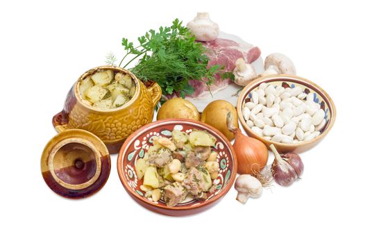 Ukrainian version of the dish Chanakhi in a clay bowl - potatoes with meat, mushrooms and haricot beans roasted in a clay pot and ingredients for its preparation on a white background
