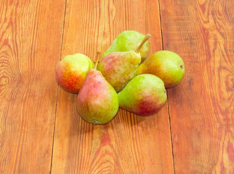 Several ripe red and green European pears on a surface of an old dark wooden planks
