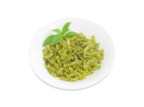 Cooked spiral pasta with sauce pesto decorated with basil twig on white dish on a white background
