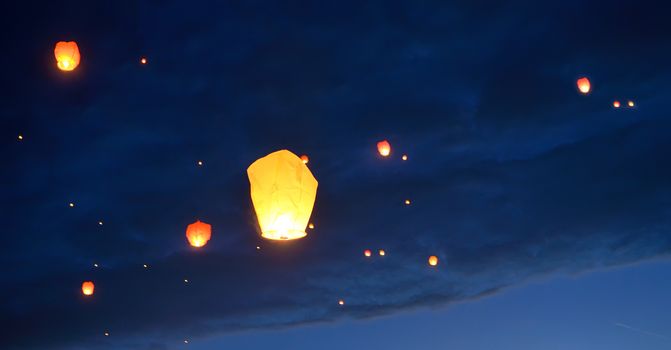 Floating paper lanterns on night sky