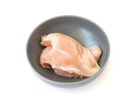 Raw chicken fillet in bowl on white background