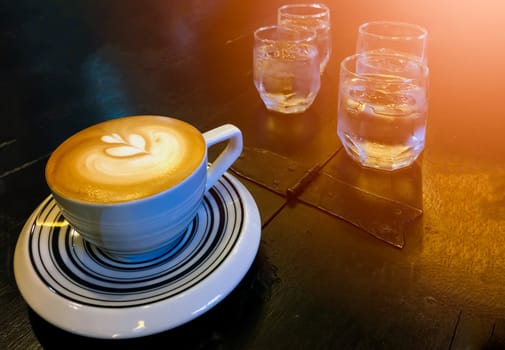 Cappuccino and water on the table with glass of water