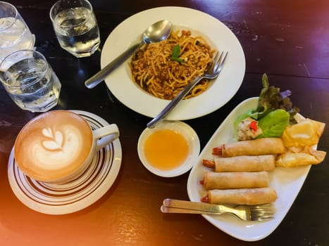 Cappuccino and water on the table with glass of water and spaketty