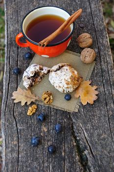 Romantic autumn still life with cookies, cup of tea, walnuts, blackthorn berries and oak leaves