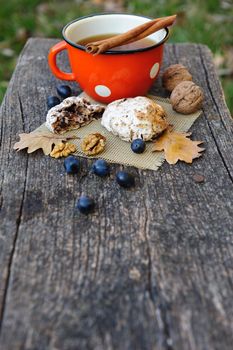 Romantic autumn still life with cookies, cup of tea, walnuts, blackthorn berries and oak leaves