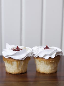 Close up of two vanilla and cherry cupcakes