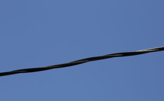 Close up of an electrical line against the deep blue sky