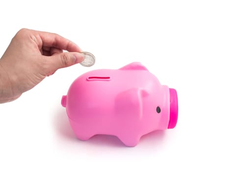 Hand putting a coin into piggy bank on white background