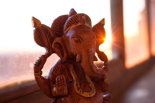 wooden figurine of indian god ganesha in warm sunlight