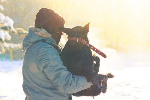 man take dog on his arm, because the dog is ill. winter