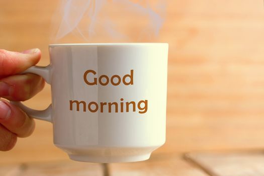 White cup on blue wooden table. Text GOOD MORNING on it