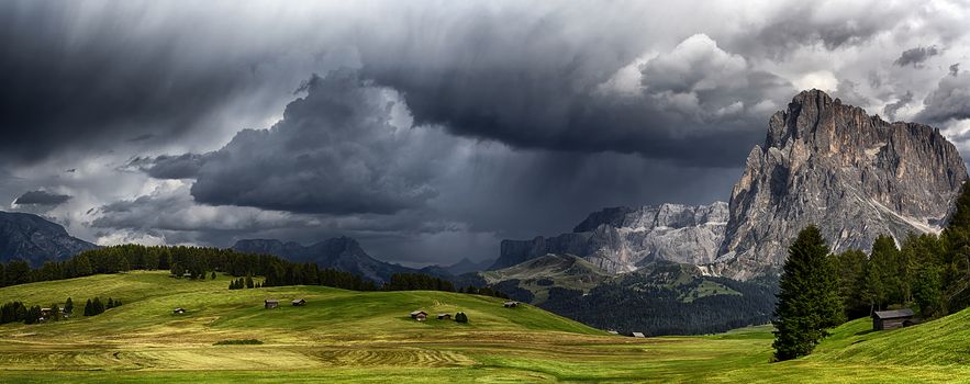 storm over the mountains Dolomiti in the summer season with green meadow illuminated of the Sun