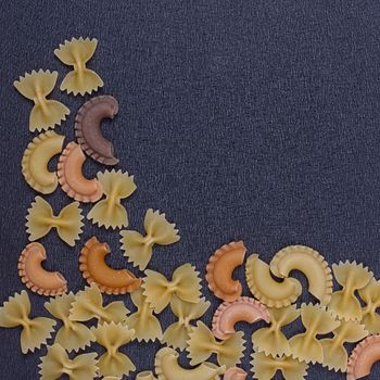 Variety of types of Italian pasta background. Set of raw dry pasta on a black slate background.