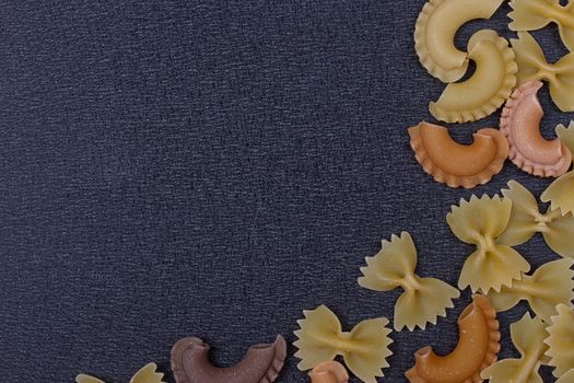 Variety of types of Italian pasta background. Set of raw dry pasta on a black slate background.