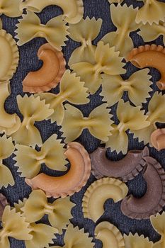 Variety of types of Italian pasta background. Set of raw dry pasta on a black slate background.