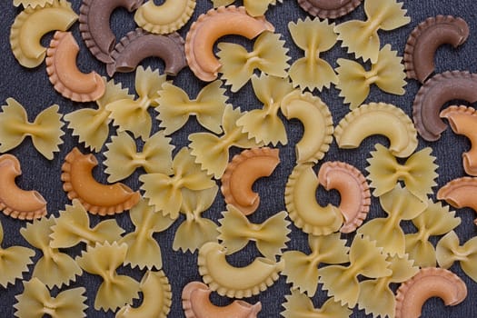 Variety of types of Italian pasta background. Set of raw dry pasta on a black slate background.