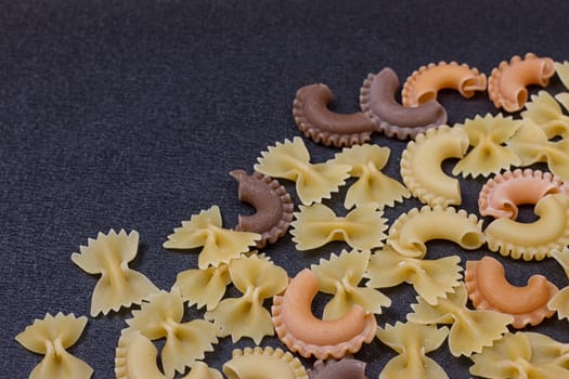 Variety of types of Italian pasta background. Set of raw dry pasta on a black slate background.