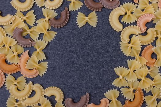 Variety of types of Italian pasta background. Set of raw dry pasta on a black slate background.