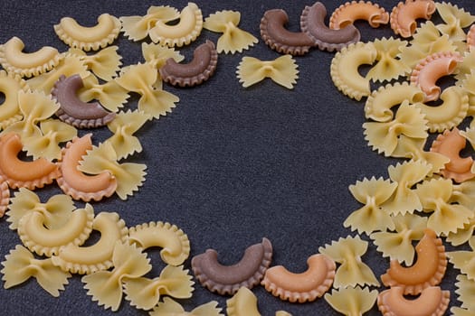 Variety of types of Italian pasta background. Set of raw dry pasta on a black slate background.