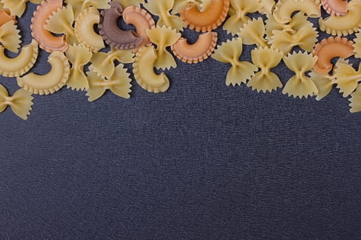 Variety of types of Italian pasta background. Set of raw dry pasta on a black slate background.