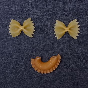 Smiling raw pasta on the black background