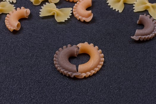 Variety of types of Italian pasta background. Set of raw dry pasta on a black slate background.