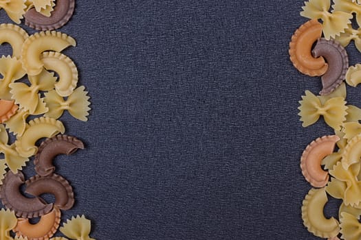 Variety of types of Italian pasta background. Set of raw dry pasta on a black slate background.