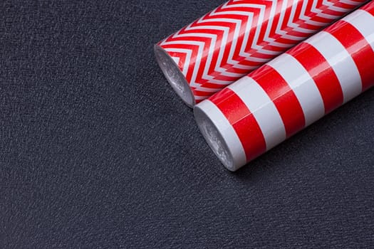 Rolls of gift wrapping paper on a black background with space for text