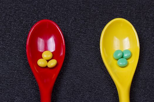 Assorted pharmaceutical medicine pills, tablets and capsules on wooden spoon. black background