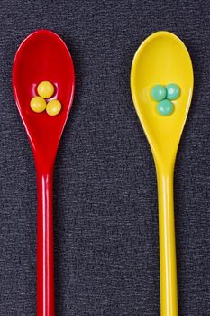 Assorted pharmaceutical medicine pills, tablets and capsules on wooden spoon. black background