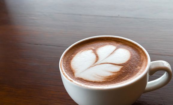 Closeup cup of hot coffee tulip latte art on wood table