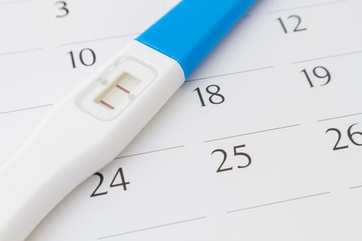 Pregnancy test on calendar background, health care concept