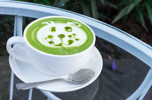 Hot matcha latte art with cute dog face cartoon on glass table