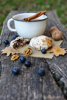 Romantic autumn still life with cookies, cup of tea, walnuts, blackthorn berries and oak leaves