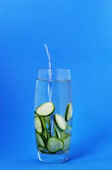 Refreshing and healthy drink of a cucumber in a glass on a blue background