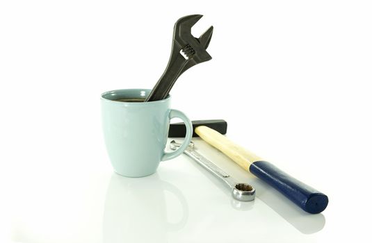 time for a coffee break during work with blue coffe cup and metal wrench or spanner and hammer isolated on white