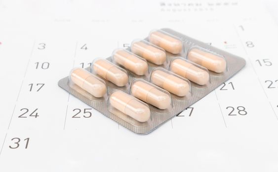 Close up pill with date of calendar background, health care and medicine concept