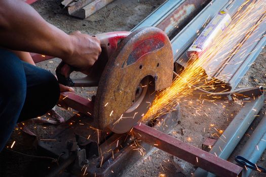 The worker in the workshop cut the steel tube angle grinder, cutting tube.